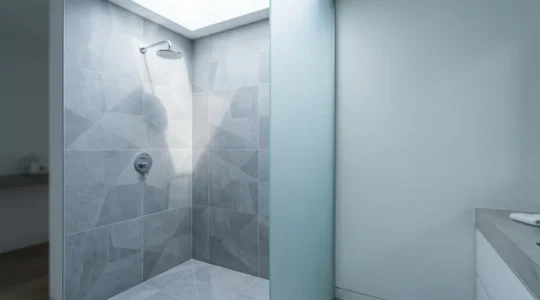 Détail d'un coin de douche à l'italienne moderne montrant la parfaite étanchéité entre le carrelage et le receveur