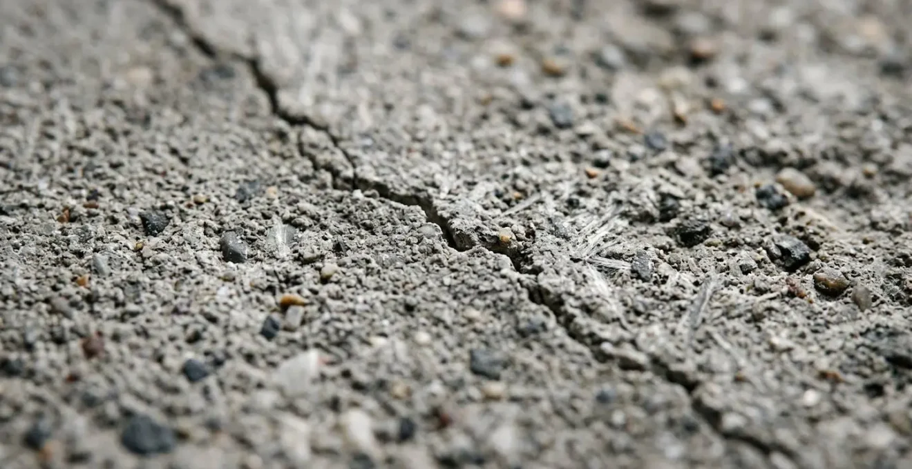 Gros plan macro d'une fissure dans du béton industriel montrant la texture cristalline et les détails de la rupture