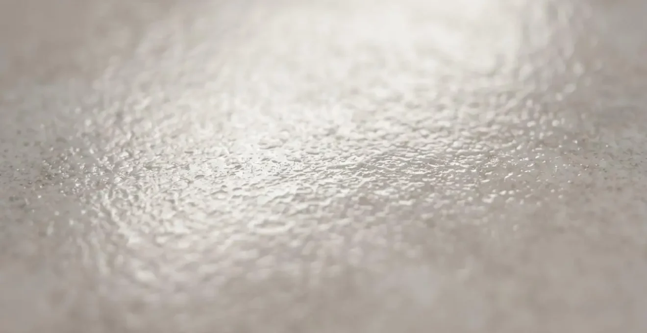 Vue macro détaillée de la surface émaillée d'un carreau de céramique révélant sa texture vitrifiée non-poreuse