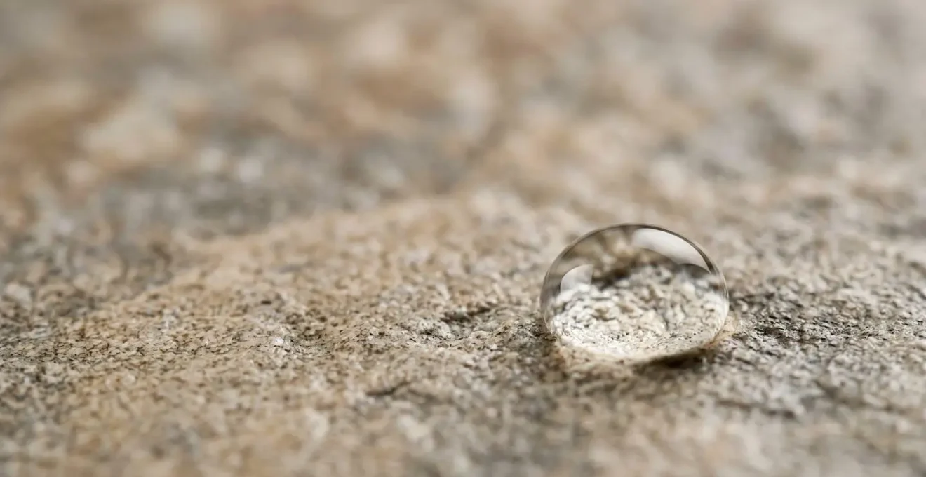 Gros plan macro sur une goutte d'eau perlant à la surface d'une dalle en grès cérame imperméable